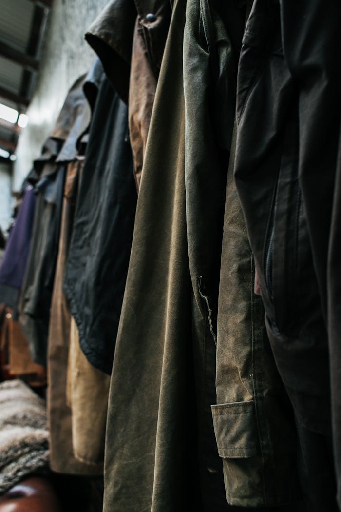 A row of vintage coats hanging indoors showcasing diverse textures and styles.